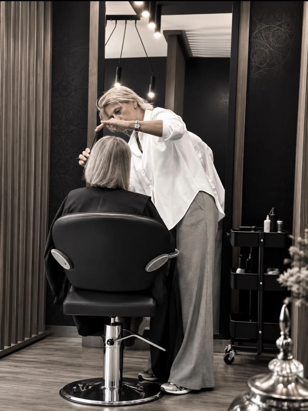 Frizerka pažljivo oblikuje kosu klijentkinje u salonu